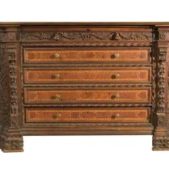 Antico canterano intarsiato con decorazioni scultoree, un vero pezzo d'antiquariato che evoca il suo significato storico.