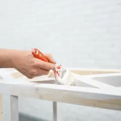 Mano che dipinge un mobile in legno con vernice a gesso, per un effetto shabby chic.