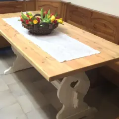 Tavolo in legno chiaro, pronto per essere lucidato, con un cestino di tulipani e una panca in legno scuro.