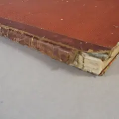 Dettaglio di una rilegatura libri vecchi con copertina rossa e dorso in pelle usurato, che mostra i segni del tempo.