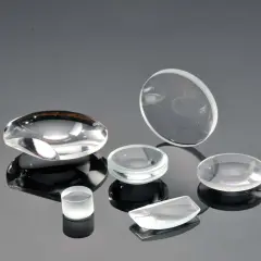 Collezione di lenti ottiche di varie forme, realizzate in vetro minerale o zaffiro, su superficie riflettente.