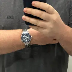 Un orologio da polso con cinturino in metallo, quadrante blu e lunetta blu, indossato su un braccio. La misura lug to lug dell'orologio è perfetta.