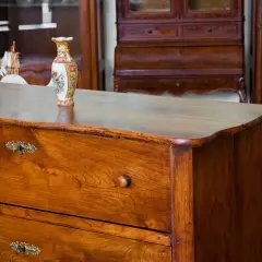 Cassettiera in legno con maniglie antiche e vaso decorato. Un esempio di come antichizzare un mobile per un tocco vintage.
