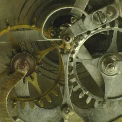 Ingranaggi dorati e argentati di un orologio, con un dettaglio dello scappamento coassiale che ne regola il movimento preciso.