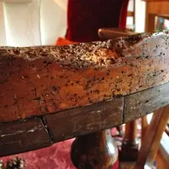Bordo di un vecchio mobile in legno, danneggiato da tarli. Necessita di disinfettare mobili vecchi per preservarlo.