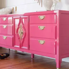 Comò rosa brillante con maniglie dorate, un esempio di come laccare un mobile già verniciato per un look audace.