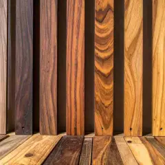 Diverse assi di legno, da chiare a scure, mostrano venature naturali. Alcune sembrano pronte per scurire il legno, altre sono già scure.