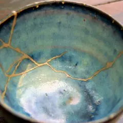 Ciotola blu con crepe dorate, un esempio di tecnica kintsugi che celebra le imperfezioni.