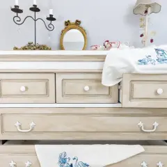 Comò in stile Chippendale rinnovato con finitura anticata. Cassetti con maniglie decorative e un ricamo di cigni su un cassetto aperto.
