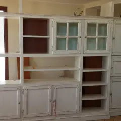 Mobile libreria in stile decapato, con ante a vetro e cassetti, che evoca un fascino vintage.