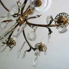 Dettagli di un lampadario a gocce in ottone, con cristalli trasparenti e perline. Un'idea per come rimodernare un lampadario a gocce con un tocco di eleganza.