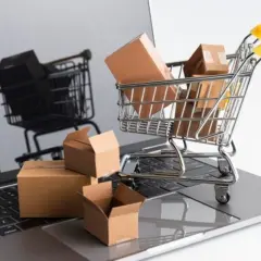 Carrello della spesa pieno di pacchi su un laptop. Il riflesso mostra un altro carrello, suggerendo un'asta online con un prezzo di riserva.