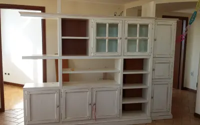 Mobile libreria in stile decapato, con ante a vetro e cassetti, che evoca un fascino vintage.