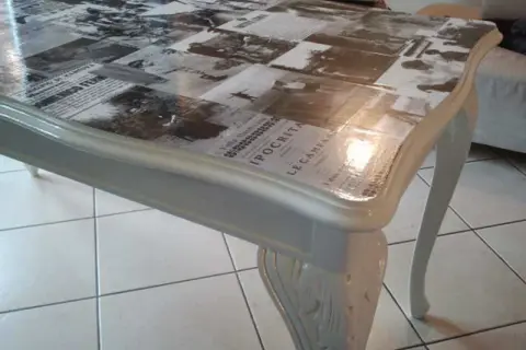 Tavolo antico trasformato con collage di giornali d'epoca sotto resina trasparente: un modo moderno per dare nuova vita ai mobili.