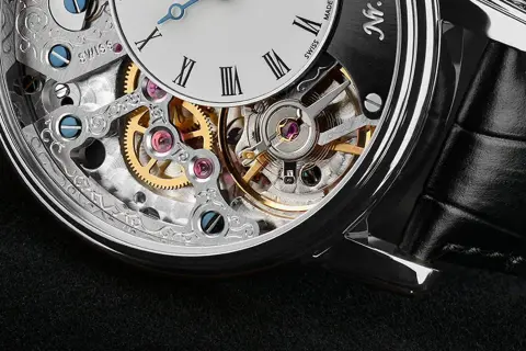Dettaglio di un orologio scheletrato con ingranaggi dorati e rubini scintillanti. La precisione svizzera incontra l'eleganza.