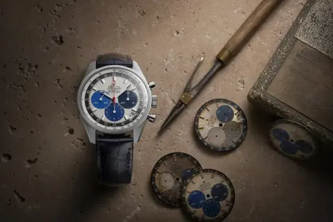 Orologio Zenith El Primero con quadrante bianco e blu, cinturino in pelle blu, circondato da quadranti di ricambio e strumenti da orologiaio.