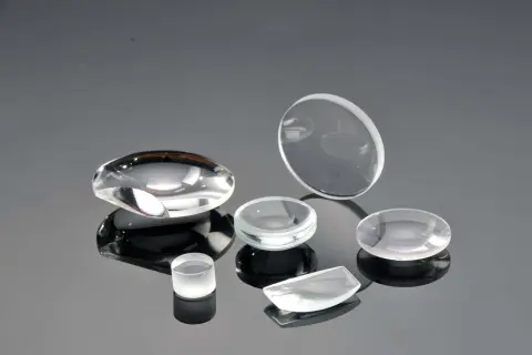 Collezione di lenti ottiche di varie forme, realizzate in vetro minerale o zaffiro, su superficie riflettente.
