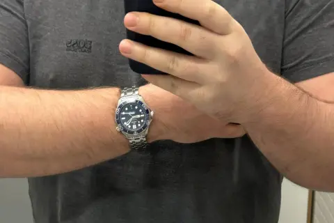 Un orologio da polso con cinturino in metallo, quadrante blu e lunetta blu, indossato su un braccio. La misura lug to lug dell'orologio è perfetta.