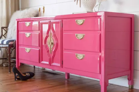 Comò rosa brillante con maniglie dorate, un esempio di come laccare un mobile già verniciato per un look audace.