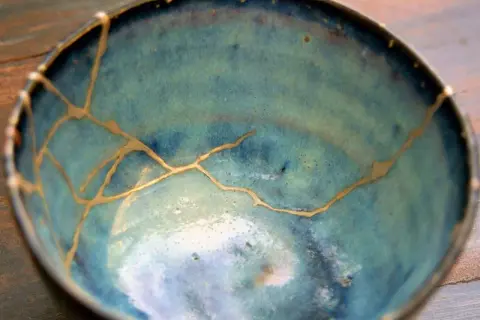 Ciotola blu con crepe dorate, un esempio di tecnica kintsugi che celebra le imperfezioni.