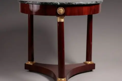 Tavolino rotondo in mogano con piano in marmo, gambe a clessidra e dettagli dorati, in perfetto stile direttorio.