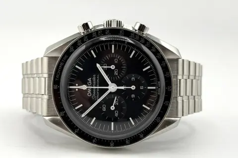 Orologio Omega Speedmaster con quadrante nero e cinturino in metallo, protetto da un **vetro esalite** che cattura la luce.
