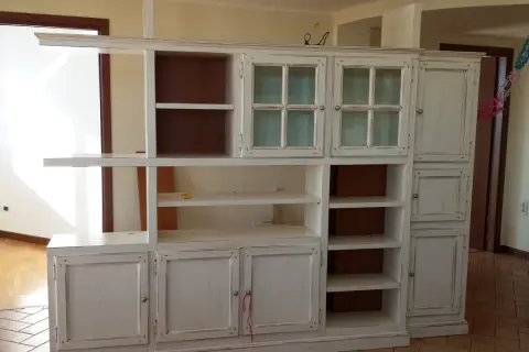 Mobile libreria in stile decapato, con ante a vetro e cassetti, che evoca un fascino vintage.