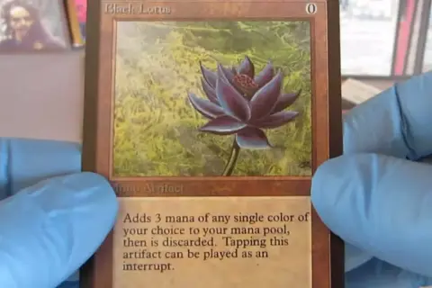 Il Black Lotus, una delle carte più costose di Magic, tenuta con guanti blu.