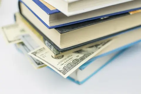Pila di libri con banconote da cento dollari inserite tra le pagine, tesori ricercati dai collezionisti.
