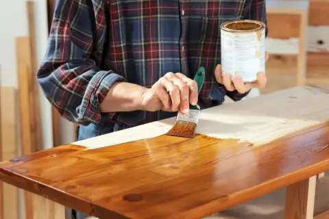 Applicazione di impregnante su legno, mostrando la differenza tra impregnante e vernice.