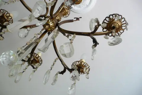 Dettagli di un lampadario a gocce in ottone, con cristalli trasparenti e perline. Un'idea per come rimodernare un lampadario a gocce con un tocco di eleganza.