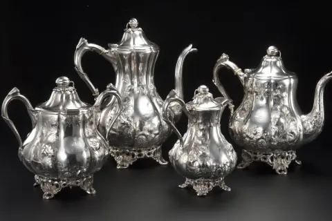 Un set di teiere e lattiera in argento antico, finemente cesellate con motivi floreali, un vero tesoro di grande valore.