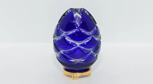 Uovo blu di cristallo intagliato, ispirato agli originali uova Fabergé, su base dorata.