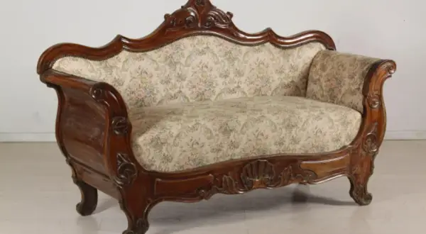 Divano in legno intagliato, stile Luigi Filippo, con seduta e schienale imbottiti in tessuto floreale.