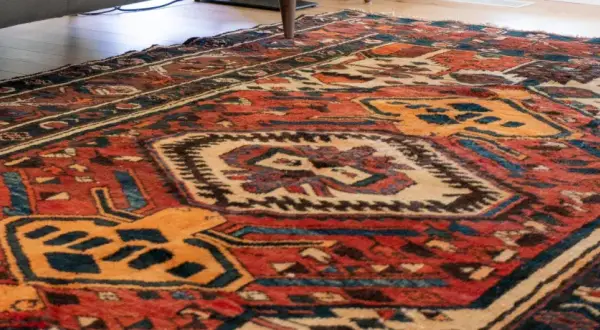 Tappeto persiano usato con motivi geometrici rossi, blu e gialli. Un pezzo d'antiquariato che conserva il suo valore.