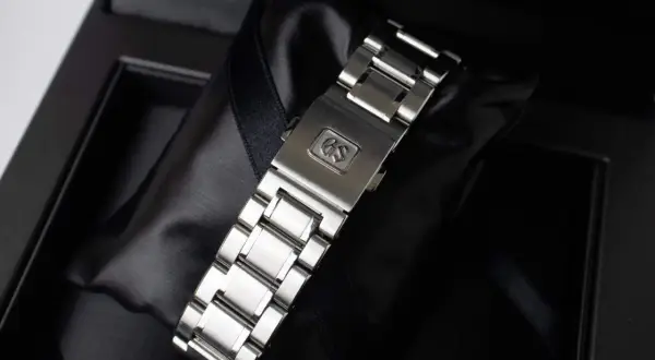 Chiusura di un bracciale per orologio in metallo, con logo GS inciso, pronto per essere indossato.