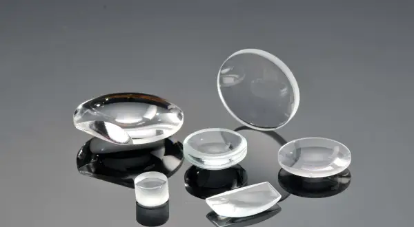 Collezione di lenti ottiche di varie forme, realizzate in vetro minerale o zaffiro, su superficie riflettente.