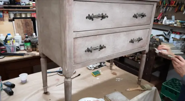 Un mobile antico in fase di restauro in stile shabby. Pennelli, colori e materiali pronti per trasformare un vecchio mobile.