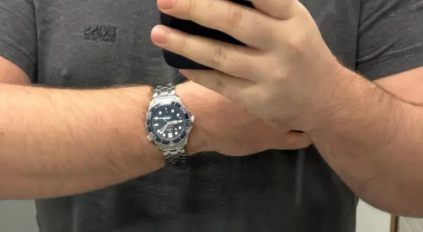 Un orologio da polso con cinturino in metallo, quadrante blu e lunetta blu, indossato su un braccio. La misura lug to lug dell'orologio è perfetta.