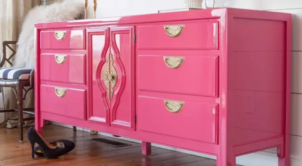 Comò rosa brillante con maniglie dorate, un esempio di come laccare un mobile già verniciato per un look audace.