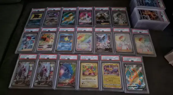 A collection of graded Pokémon cards, including Charizard, Mewtwo, and Pikachu, displayed in protective cases.