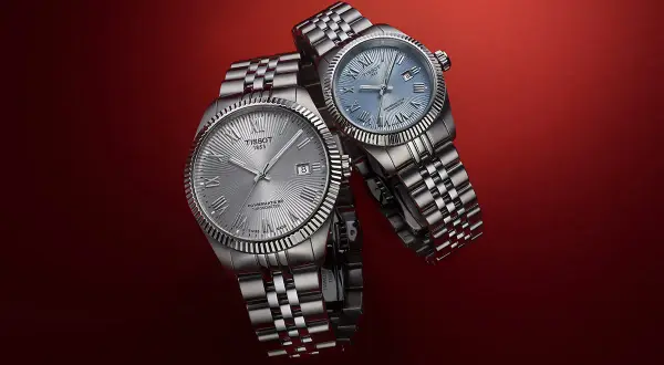 Due orologi Tissot con quadrante argentato e blu, entrambi con movimento automatico Powermatic 80, su sfondo rosso.