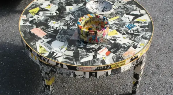 Tavolino rotondo con tecnica decoupage mobili, ricoperto di immagini in bianco e nero e fumetti colorati.