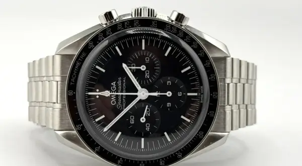 Orologio Omega Speedmaster con quadrante nero e cinturino in metallo, protetto da un **vetro esalite** che cattura la luce.