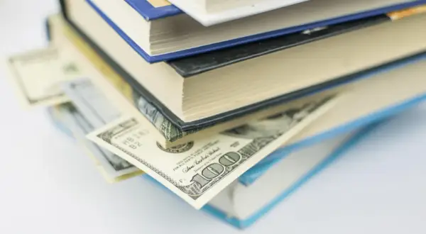 Pila di libri con banconote da cento dollari inserite tra le pagine, tesori ricercati dai collezionisti.