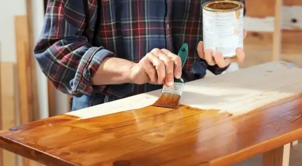 Applicazione di impregnante su legno, mostrando la differenza tra impregnante e vernice.