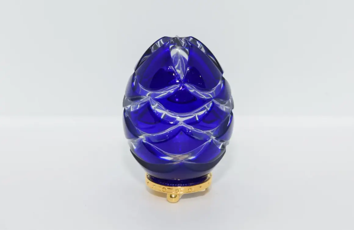 Uovo blu di cristallo intagliato, ispirato agli originali uova Fabergé, su base dorata.