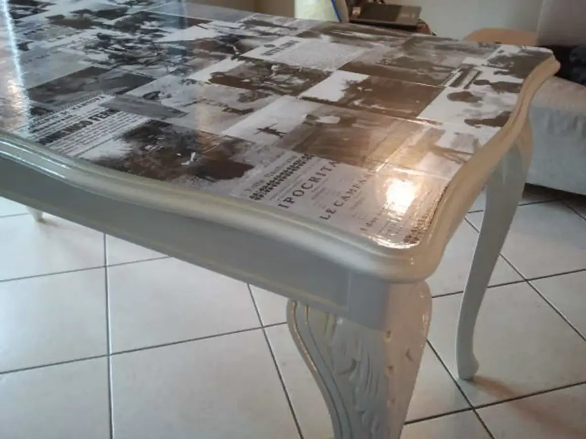 Tavolo antico trasformato con collage di giornali d'epoca sotto resina trasparente: un modo moderno per dare nuova vita ai mobili.