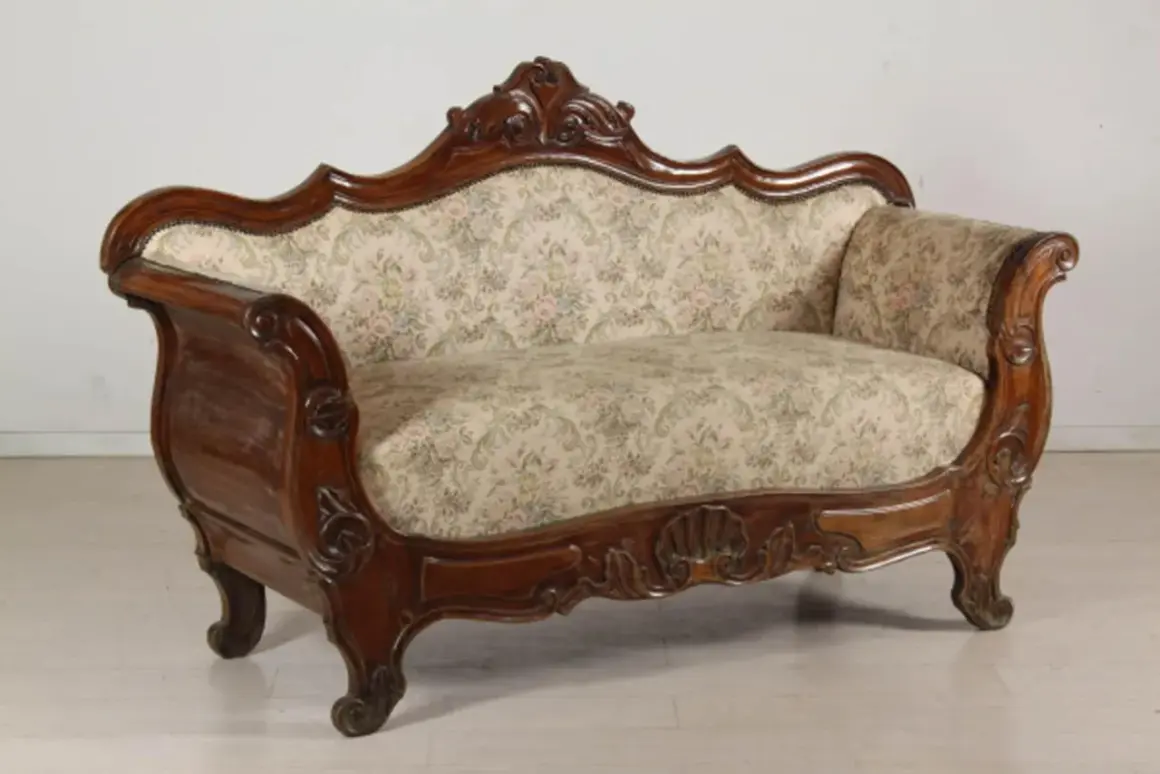 Divano in legno intagliato, stile Luigi Filippo, con seduta e schienale imbottiti in tessuto floreale.