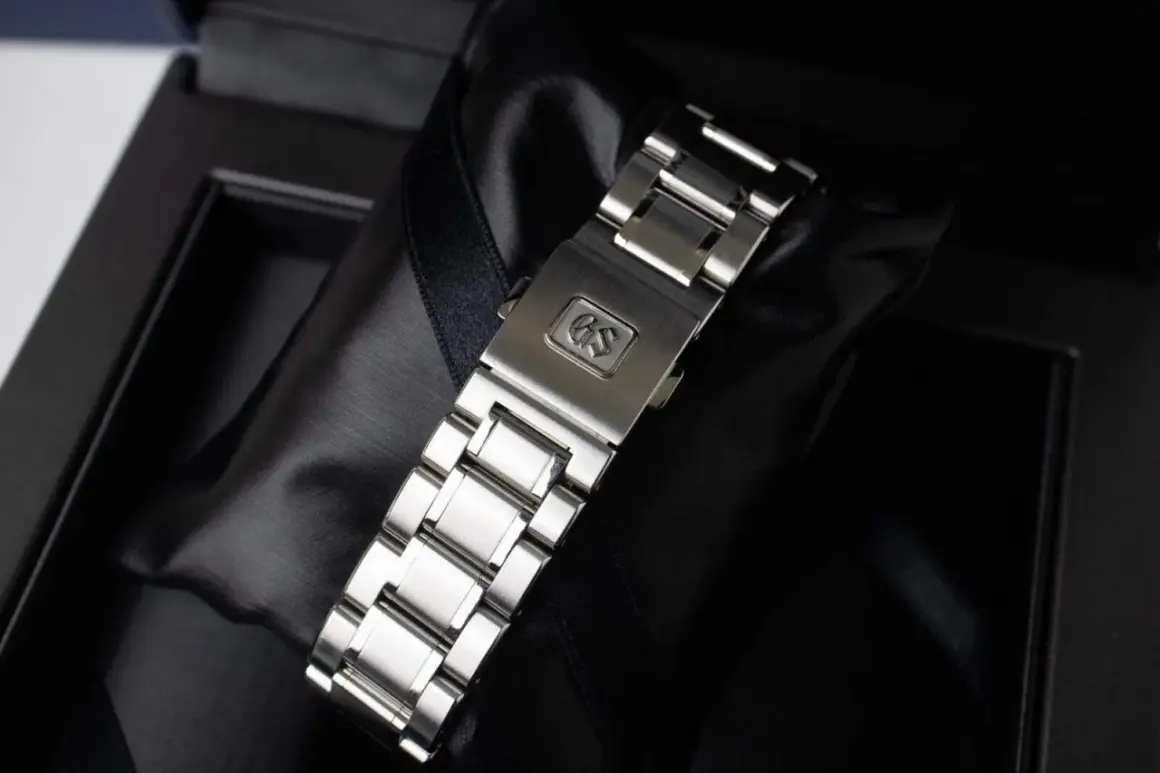 Chiusura di un bracciale per orologio in metallo, con logo GS inciso, pronto per essere indossato.